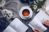Two open faced books with coffee cup and flowers create peaceful aesthetic.